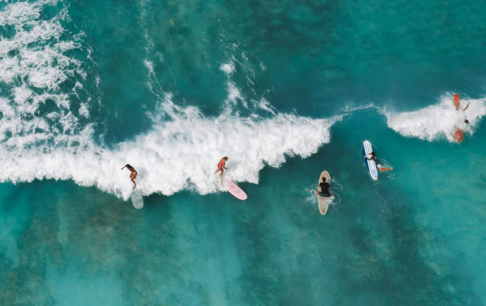 Aerial shot capturing surfers enjoying the ocean waves, showcasing water sports adventure.